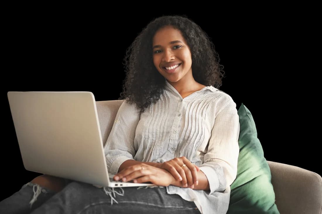 Smiling young woman using a laptop at home, browsing the internet.